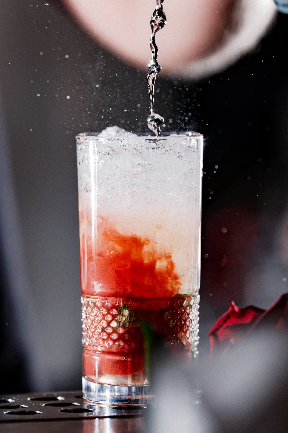 Red cocktail mixing under pouring stream