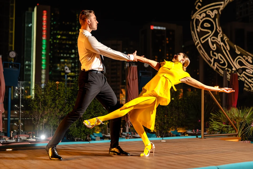 Dance partners stretching across outdoor stage