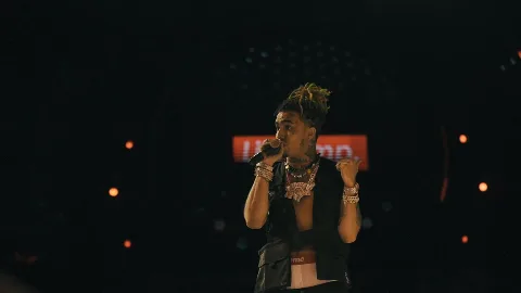 A performer holding a microphone on a dark stage.