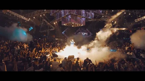 A concert crowd beneath bright stage smoke.