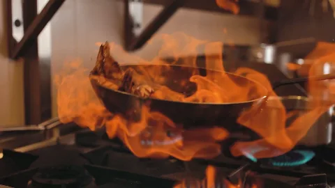 A chef cooking over a bright pan flame.